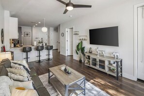 A modern living room with a sofa, coffee table, and a TV mounted on the wall. - Escape To The Twilight Bungalow 1BR Tempe TownLake (Tempe)