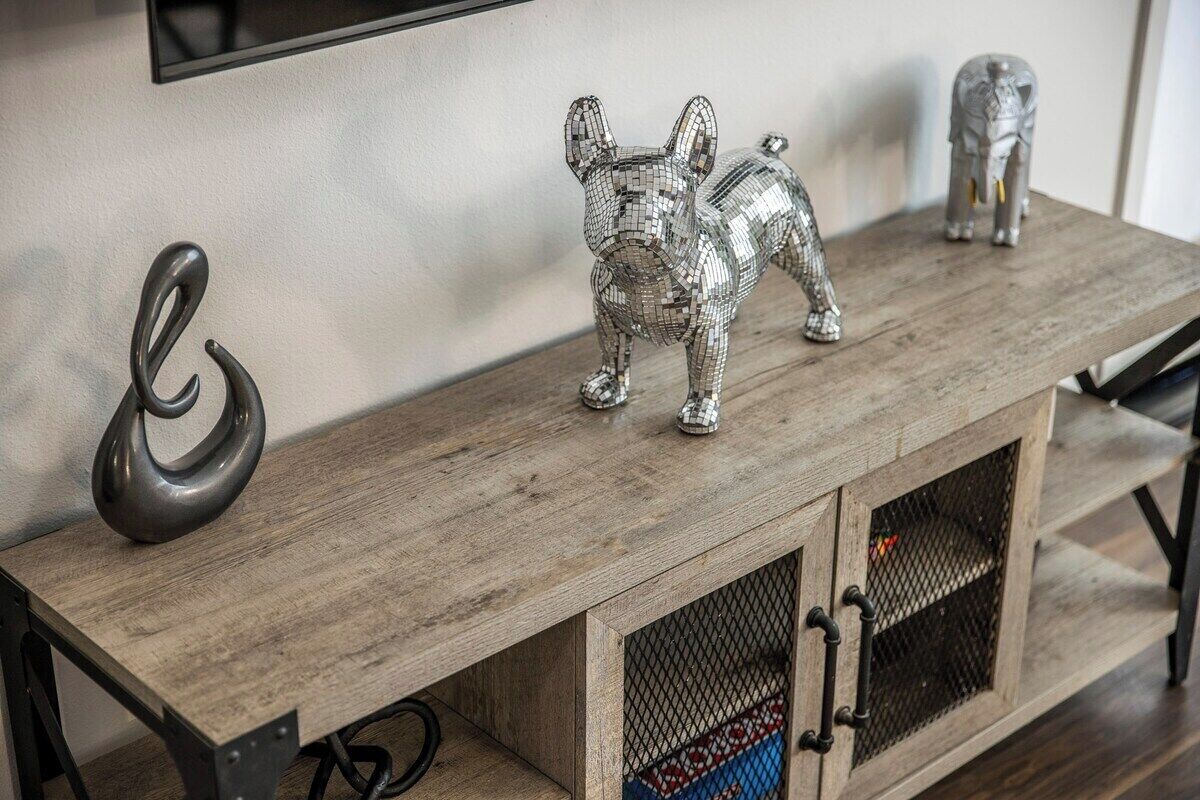 A wooden cabinet with a mesh door, a decorative dog figurine, and a small elephant figurine on top.