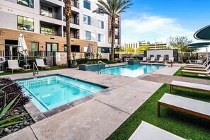 Ein Hotelpoolbereich mit zwei Pools, Liegestühlen und Palmen.