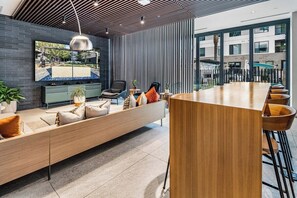 Un intérieur moderne avec un long banc en bois, un coin repas et une grande fenêtre donnant sur l’extérieur.