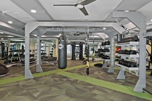 Une salle de sport équipée de matériel de musculation, d’un sac de frappe et d’un mur recouvert de miroirs.
