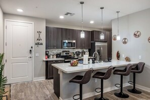 A modern kitchen with dark wood cabinets, stainless steel appliances, and a central island with bar stools. - Escape To N. Scottsdale 2BR Saguaro Cactus Retreat (Phoenix)