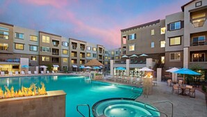 Ein Hotelpoolbereich mit Whirlpool, Liegestühlen und Sonnenschirmen.