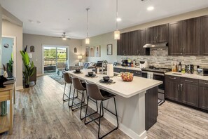 A modern kitchen with a central island, dark wood cabinets, and a large window overlooking a balcony. - Escape To N. Scottsdale Modern & Chic 1BR Suite (Phoenix)