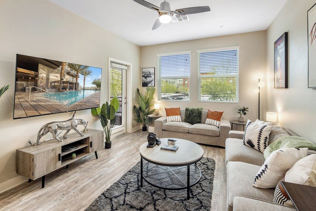 A modern living room with a pool view, a ceiling fan, and a sofa set.