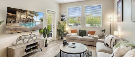 A modern living room with a pool view, a ceiling fan, and a sofa set.