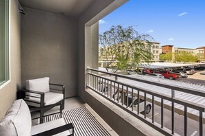 A balcony with a view of parked cars and buildings, a chair, and a patterned rug. - Escape To Hollywood Hideaway 2BR King Bed Suite (Phoenix)