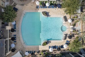 Luftaufnahme eines Hotelpools mit Liegestühlen und Sonnenschirmen.