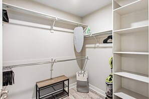 A walk-in closet with open shelving, a bench, and a vacuum cleaner. - Escape to N. Scottsdale 1BR Bohemian Desert Dream (Phoenix)