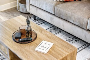 Ein Holztisch mit Fernbedienung, einem Buch und einem Kerzenhalter.