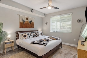 A bedroom with a bed, a ceiling fan, a window with blinds, and a wall clock. - Escape to N. Scottsdale 1BR Bohemian Desert Dream (Phoenix)
