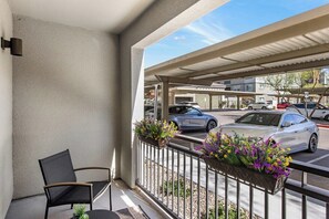 Ein Balkon mit einem Stuhl, einem kleinen Tisch und Blumenkästen.