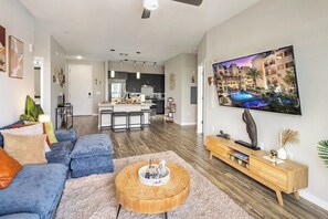 Ein modernes Wohnzimmer mit einer Couch, einem Couchtisch und einem an der Wand montierten Fernseher.
