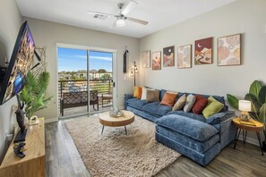 Ein Wohnzimmer mit blauem Sofa, Couchtisch, Fernseher und Kunstwerken an der Wand.