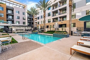 A modern hotel with a swimming pool, outdoor seating, and palm trees. - Escape To The Lion's Den 1BR King Bed Suite! (Tempe)