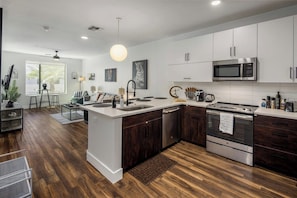 A modern kitchen with a central island, stainless steel appliances, and a dining area with a view. - Escape To The Lion's Den 1BR King Bed Suite! (Tempe)