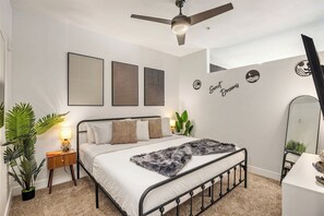 A bedroom with a bed, a ceiling fan, wall art, and a mirror. - Escape To The Tempe Penthouse King Bed Studio (Tempe)