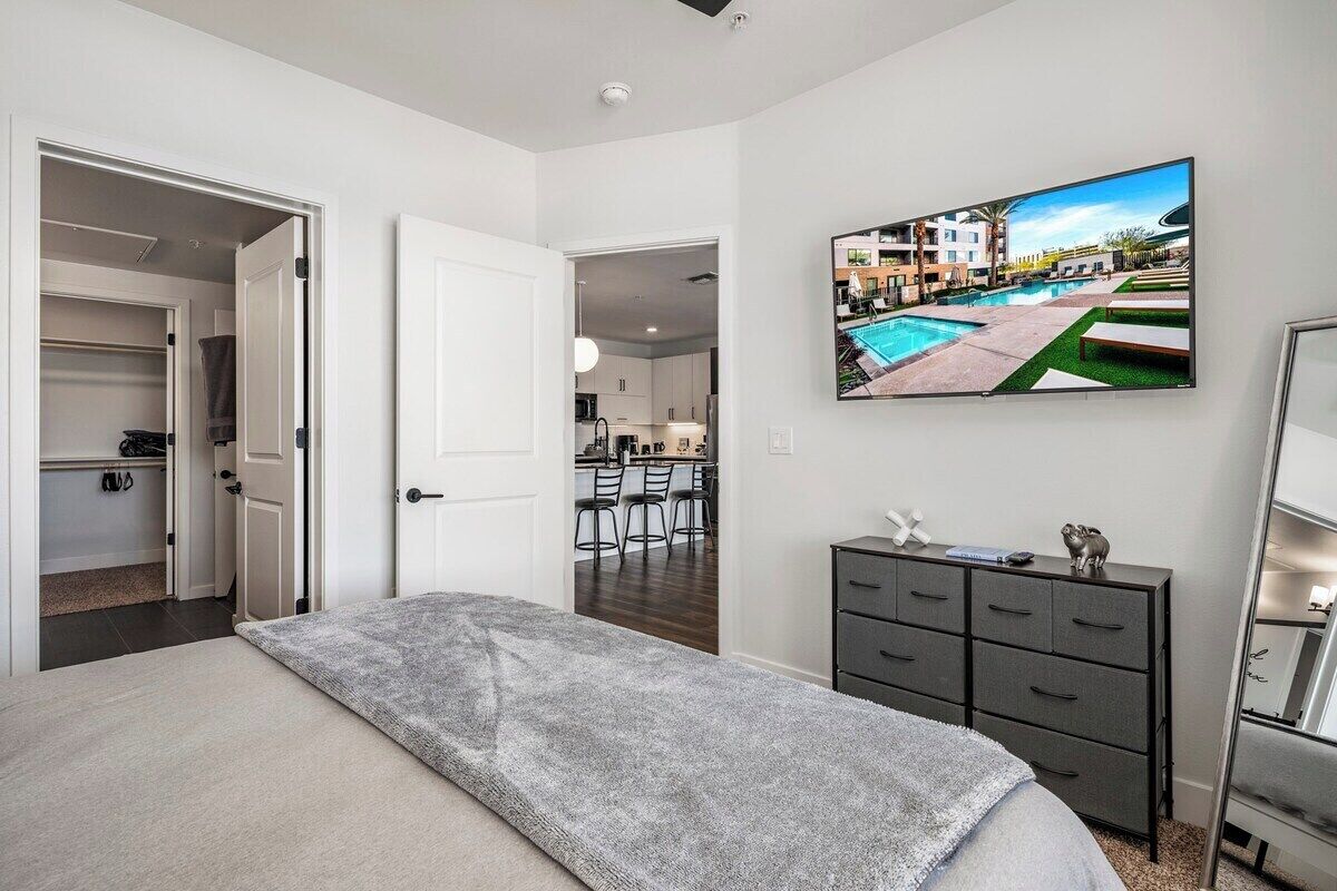 A bedroom with a bed, a dresser, and a TV displaying a pool view.
