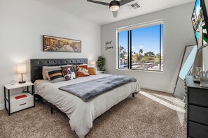 A bedroom with a bed, nightstand, lamp, and a large window with a view. - Escape to Trendy & In Vogue 2 BR Tempe Town Lake (Tempe)