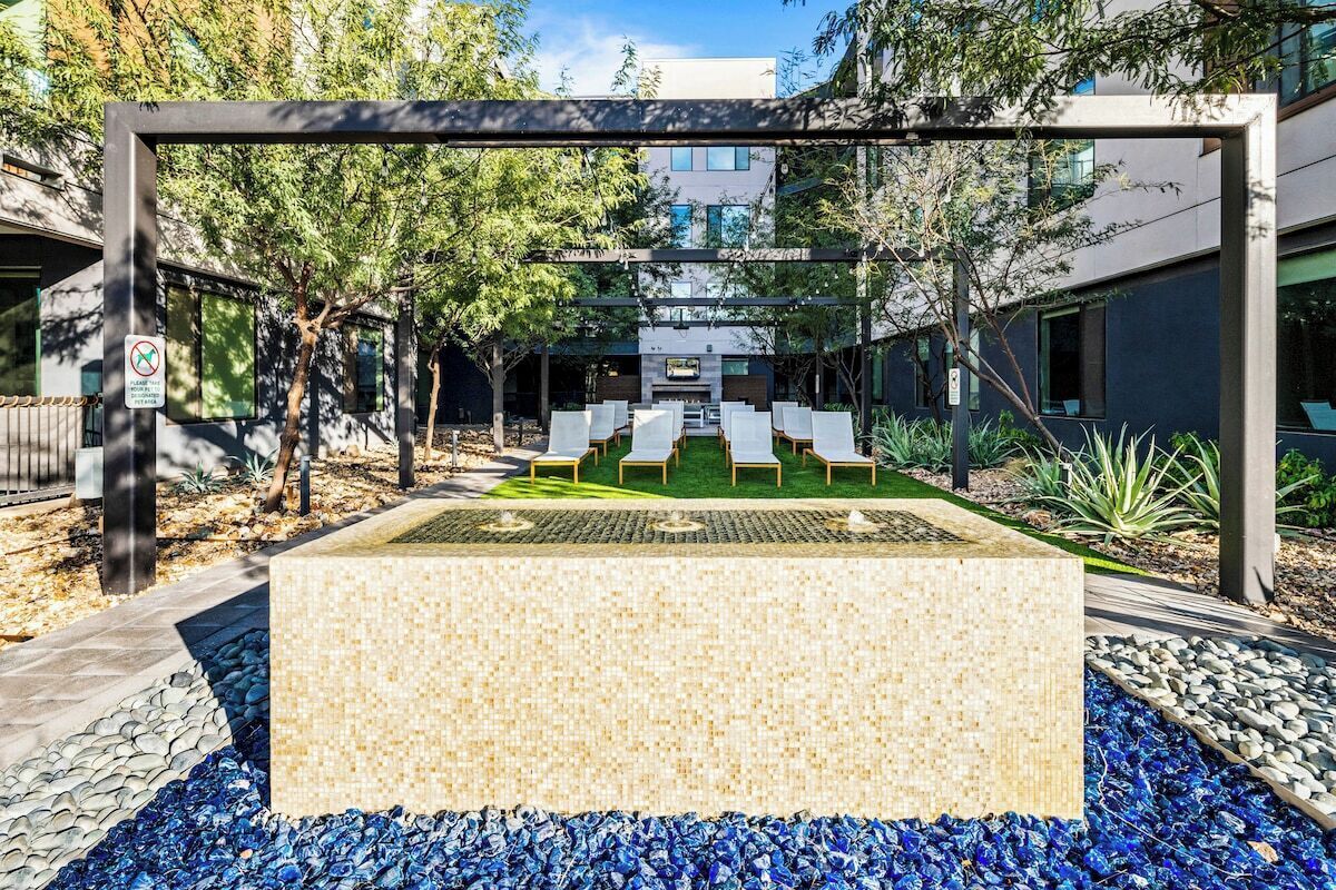 Un espacio exterior con mobiliario moderno, que incluye una jardinera rectangular y un conjunto de asientos.