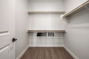 Ein Zimmer mit einer weißen Tür, einem Kleiderständer und einem Regal.