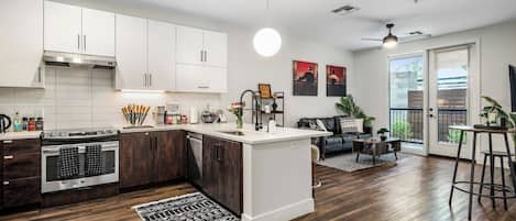 Una cocina moderna con armarios blancos, una isla central y una zona de comedor con un sofá de cuero negro.