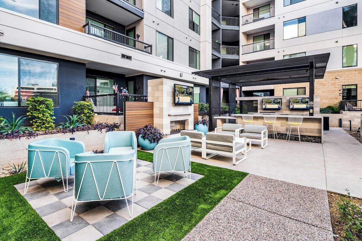 Een moderne buitenruimte met terras, zitplaatsen en een barbecue.