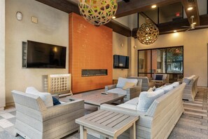 A modern lounge area with seating, a flat-screen TV, a fireplace, and a large window. - Escape To The Golden Equestrian 2BR Tempe Townlake (Tempe)