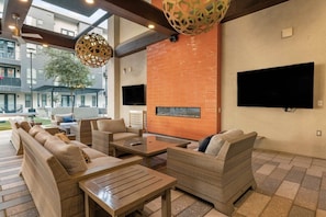 Un espace de détente extérieur moderne, avec des meubles en osier, un téléviseur à écran plat et un mur en briques.