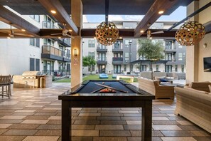 Ein Billardtisch in einer Lounge mit Blick auf ein mehrstöckiges Gebäude im Hintergrund.