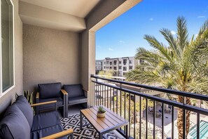 Ein Balkon mit einer Couch, einem kleinen Tisch und einem Blumentopf.