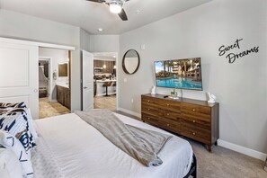 Un dormitorio con cama, cómoda, televisor y pared con una cita motivacional.