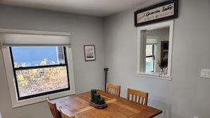 A dining area with a wooden table and chairs, a window with a view, and a sign on the wall.