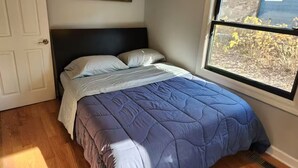 A bedroom with a bed, a window with a view, and a door.