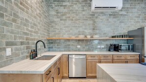 A modern kitchen with a built-in dishwasher, a microwave, and a brick backsplash. - Casa VistaMar Spacious 5-bedroom villa built around a tree! (Potrero)