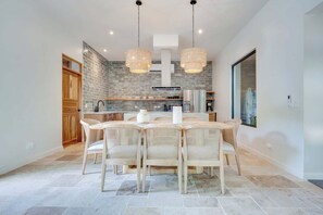 A modern kitchen with a brick backsplash, a dining area with wicker chairs, and pendant lighting. - Casa VistaMar Spacious 5-bedroom villa built around a tree! (Potrero)