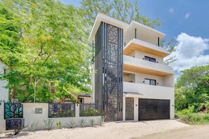 Ein modernes Mehrfamilienhaus mit Flachdach, Garage und schmiedeeisernem Zaun.