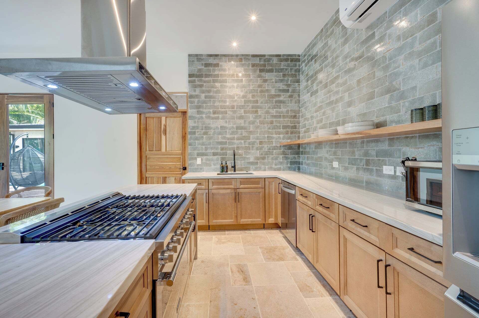 Una cocina moderna con estufa a gas, armarios de madera y un backsplash de ladrillo.