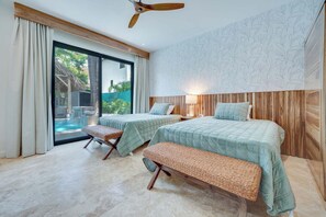 Ein Hotelzimmer mit zwei Betten, einer Bank, einem Deckenventilator und Blick auf ein Außenbecken.