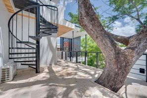 A modern building with a spiral staircase, a large tree, and a balcony with a view of the sky. - Casa VistaMar Spacious 5-bedroom villa built around a tree! (Potrero)