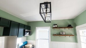 A kitchen with green cabinets, a white refrigerator, a microwave, and a window with blinds.