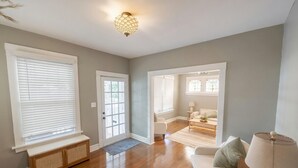 A spacious living room with hardwood flooring, a bench, a sofa, and a lamp.