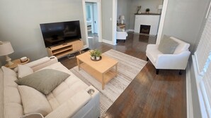 A living room with a television, sofa, coffee table, and fireplace.