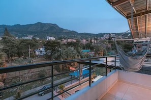Un balcón con vistas a una zona residencial, una silla colgante y una piscina.