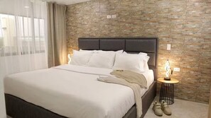 A hotel room with a large bed, a nightstand, and a brick-patterned wall. - Entire Building for Groups of 16+ in Medellín (Medellín)