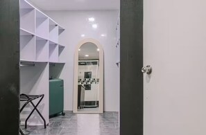 A hallway with a tiled floor, a white door with a round mirror, and a metal rack with a towel. - Entire Building for Groups of 16+ in Medellín (Medellín)