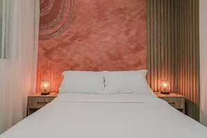A bed with white bedding, two bedside lamps, and a textured wall behind. - Entire Building for Groups of 16+ in Medellín (Medellín)