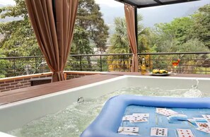 A hot tub with cards floating on the water, surrounded by a wooden deck and a metal railing. - Entire Building for Groups of 16+ in Medellín (Medellín)