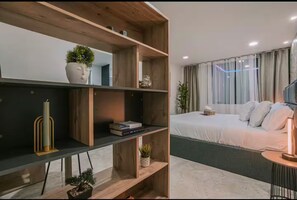 A modern bedroom with a bed, a bedside table, and a built-in shelf unit with decorative items. - Entire Building for Groups of 16+ in Medellín (Medellín)