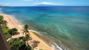 A beach with clear turquoise water, a sandy shore, and palm trees. - Mahana Resort | Oceanfront Studio Sleeps 2 | Car Incl. w/ 6+ Nights | MAH-1002 by KBM (Lahaina)